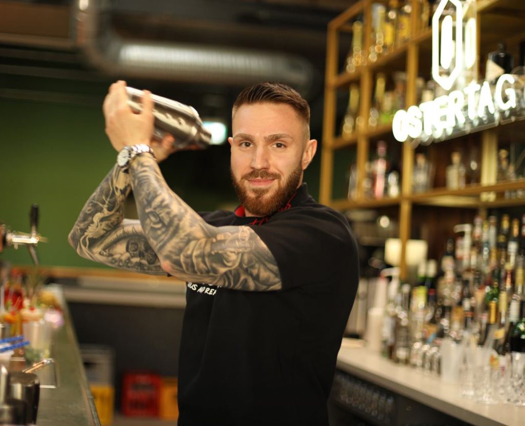 Tim Faschian mit Cocktail Shaker an der Bar mixt einen Drink